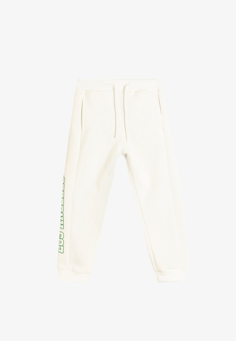 Hvide sweatpants med en afslappet pasform, der har sidelommer og en elastisk talje. Grøn tekst langs venstre ben tilføjer detaljer.