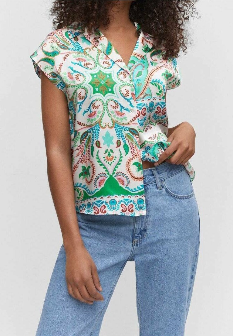 Blusa de manga corta impresa en tela ligera, con un colorido patrón de paisley en tonos verdes, azules y rojos. Combinada con jeans de mezclilla.