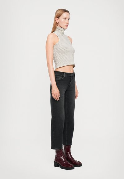 Striped gray and white cropped turtleneck paired with black straight-leg jeans and shiny burgundy ankle boots, presenting a monochromatic look.