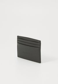 Porte-cartes en cuir noir avec quatre emplacements pour cartes et une texture lisse. Design simple, forme rectangulaire, branding minimal à l'avant.
