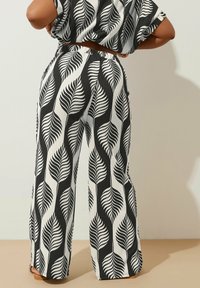 Pantalones de pierna ancha con un patrón de hojas en blanco y negro, fabricados en un tejido texturizado y con una cintura elástica, que presentan un ajuste de talle alto.