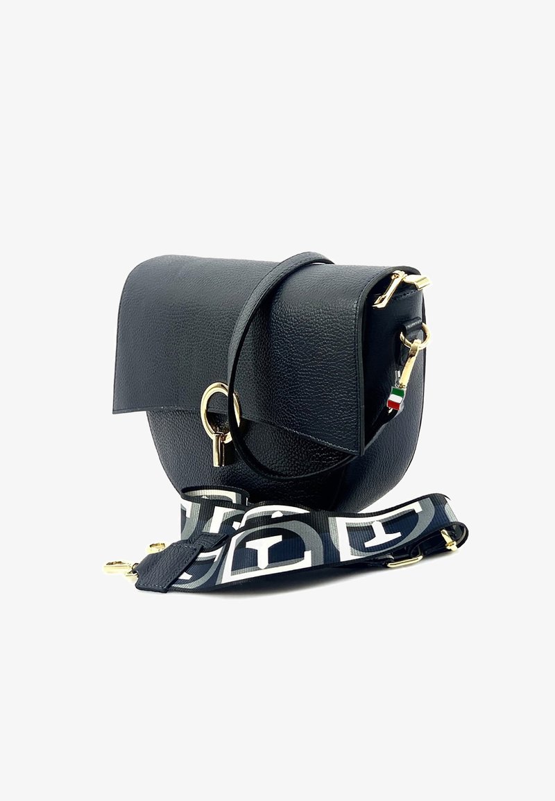 Sac à main en cuir noir avec une forme courbée, quincaillerie dorée et une bandoulière à motif avec des accents noir et blanc.