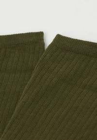 Calcetines verdes acanalados con una textura suave y puños elasticados, que presentan un diseño sin costuras y sin patrones o acentos adicionales.