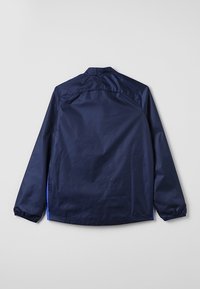 Navy blue lightweight jacket with a stand collar, elastic cuffs, and side panels; smooth texture with a simple design.