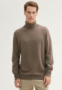 Brązowy sweter z golfem, wykonany z miękkiego, teksturowanego materiału. Posiada długie rękawy i dopasowaną talię. Gładkie wykończenie bez widocznych wzorów.