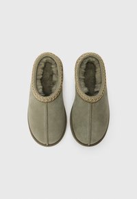 Gröna mockasinsandaler med en mjuk, texturerad foder. Har en flätad kant vid öppningen och en platt, rund sula.