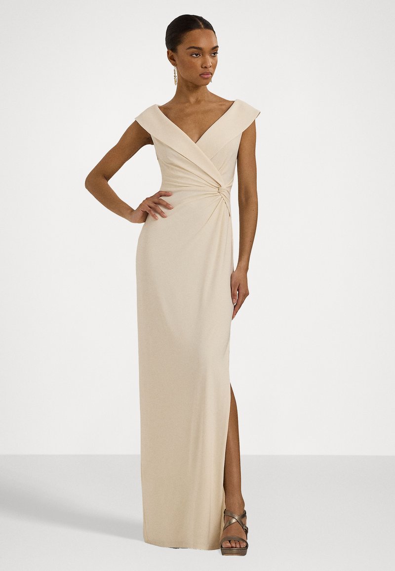 Vestido beige hasta el suelo con mangas cortas, diseño retorcido en la cintura y una abertura alta en el muslo. Tejido suave con un ligero estiramiento.