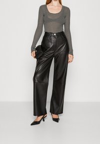 Černé kožené kalhoty s širokými nohavicemi spojené s černo-bílým pruhovaným topem s dlouhým rukávem. Top má výstřih do kulata a přiléhavý střih.