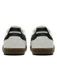 Scarpe sportive bianche e verde scuro con una finitura in pelle texturizzata, dotate di una suola in gomma marrone e due dettagli accenti sui pannelli posteriori.