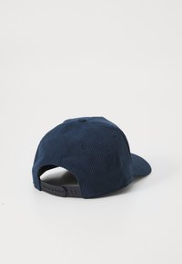 Navy corduroy cap with a curved brim, textured fabric, six-panel design, and adjustable snapback closure at the rear.