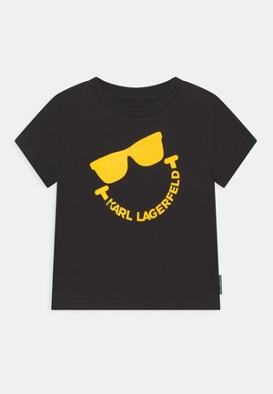 Camiseta negra de manga corta con un gráfico de gafas de sol amarillas y el texto "KARL LAGERFELD" curvado debajo de las gafas en el frente.