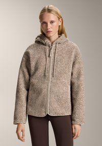 Brązowy polarowy hoodie o teksturowanej powierzchni, w neutralnym odcieniu, z pełnym zamkiem błyskawicznym i kapturem ze sznurkiem. Posiada kontrastowe wykończenia wzdłuż brzegów.