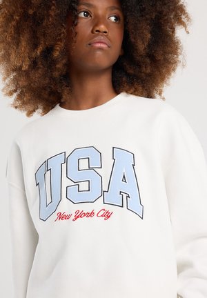 Witte sweatshirt met geborduurde "USA" en "New York City" in blauw en rood. Heeft een ronde hals en een zachte stofstructuur.