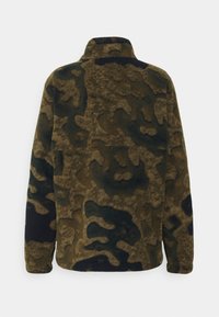 Chaqueta de forro polar en un patrón de camuflaje marrón y verde oscuro, con mangas largas y cuello alto, vista desde la espalda.