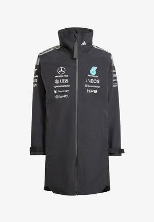 Black long racing team jacket with full front zipper, high collar, and white sponsor logos including Mercedes, Petronas, and INEOS.