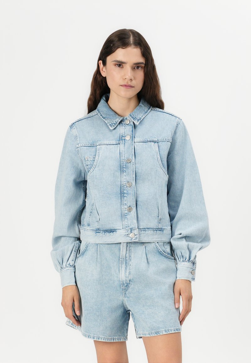 Veste en denim bleu clair avec un col, fermeture à boutons et poches avant. Elle présente des manches bouffantes et un design court.