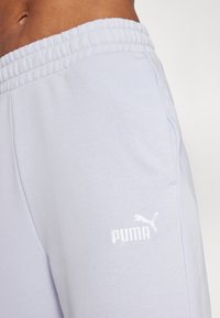 Gaiši zili sporta bikses ar elastīgu jostu un sānu kabatām. Balts izšūts Puma logo kreisajā augšstilbā. Gluda kokvilnas tekstūra.