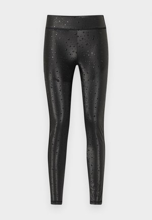 Svarte høytlivsblanke leggings med vanndråpemønster, tettsittende og med ben i full lengde mot ensfarget bakgrunn.