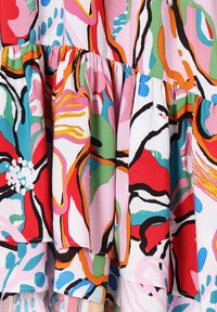 Látka s vrstvami volánů, která má abstraktní květinový vzor v červené, růžové, zelené, modré, oranžové, černé a bílé barvě.