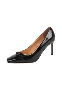 Décolleté neri in vernice con punta affusolata, cinturino decorativo con una decorazione circolare e un sottile tacco a stiletto. Texture liscia.