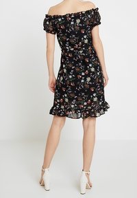 Svart blommig klänning med avtagna axlar, kort volangslutning, genomskinligt tyg, med små färgglada blommönster.