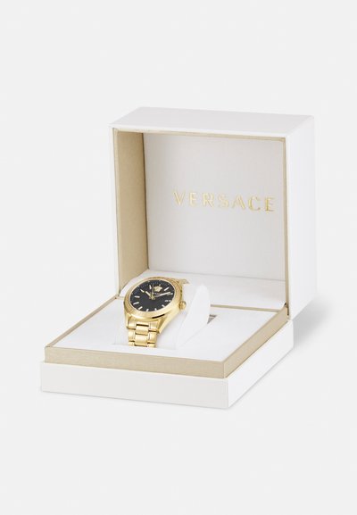 Versace kell münterkulda metallist, millel on must kellanägu, kuldsed detailid ja linkkäevõru, esitatud valges ja kuldsetes karpides.