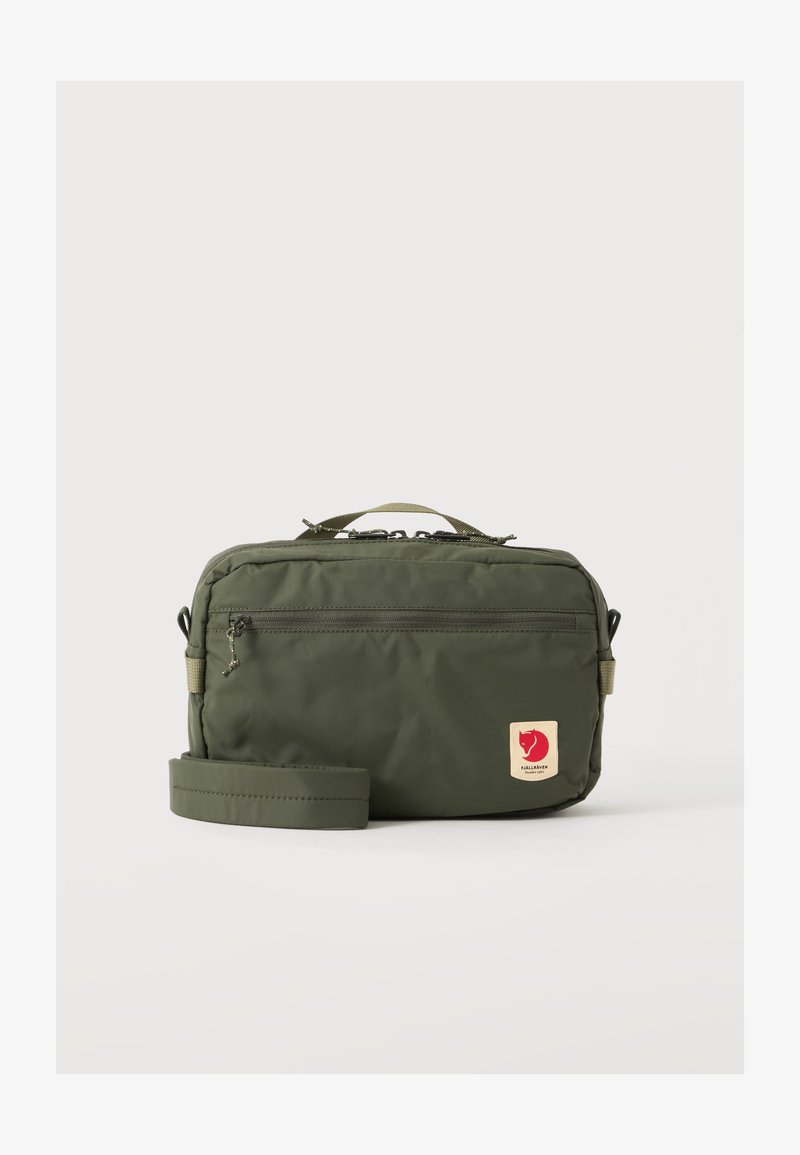 Πράσινο ορθογώνιο τσάντα crossbody με μπροστινή τσέπη με φερμουάρ, ρυθμιζόμενο λουρί, επάνω λαβή και κόκκινο λογότυπο αλεπούς στο μπροστινό μέρος.