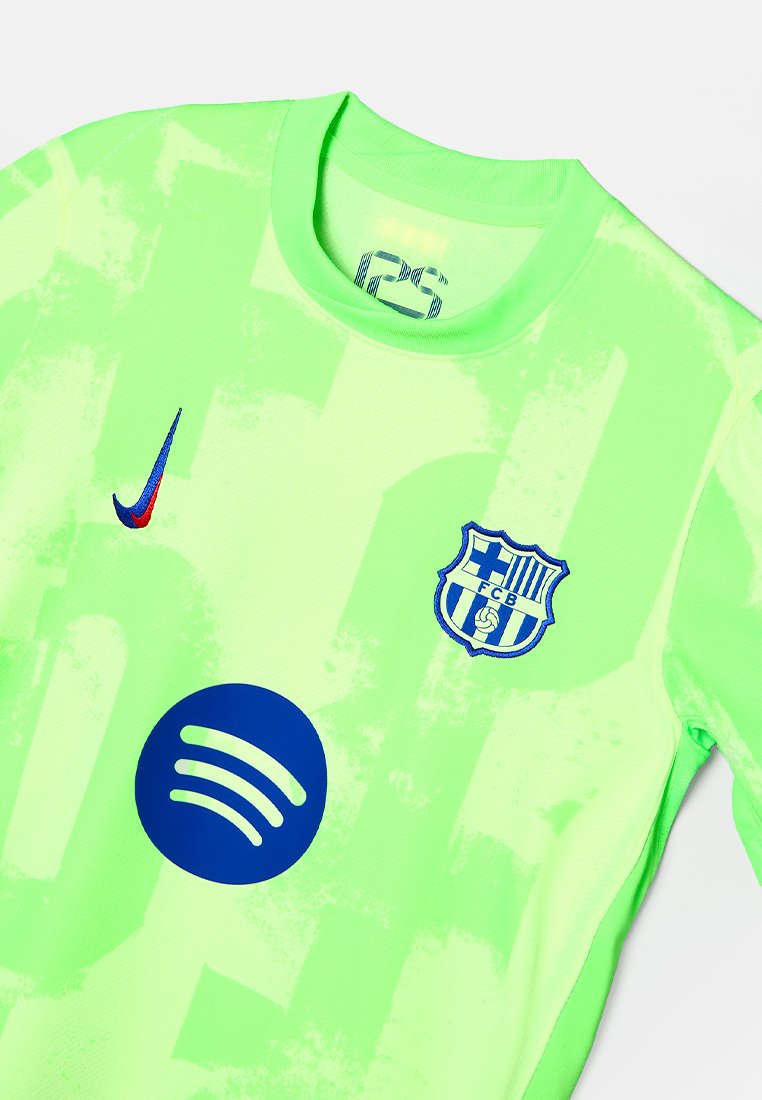 Zielony szalik Nike ma teksturowany wzór, na przodzie znajduje się niebieskie logo Barcelony oraz okrągłe, ciemnoniebieskie logo Spotify.