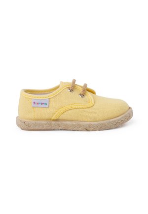 Zapatilla de lona amarilla con puntera redonda, suela de yute natural y cordones marrón claro. Presenta una pequeña etiqueta de marca colorida en el lateral.