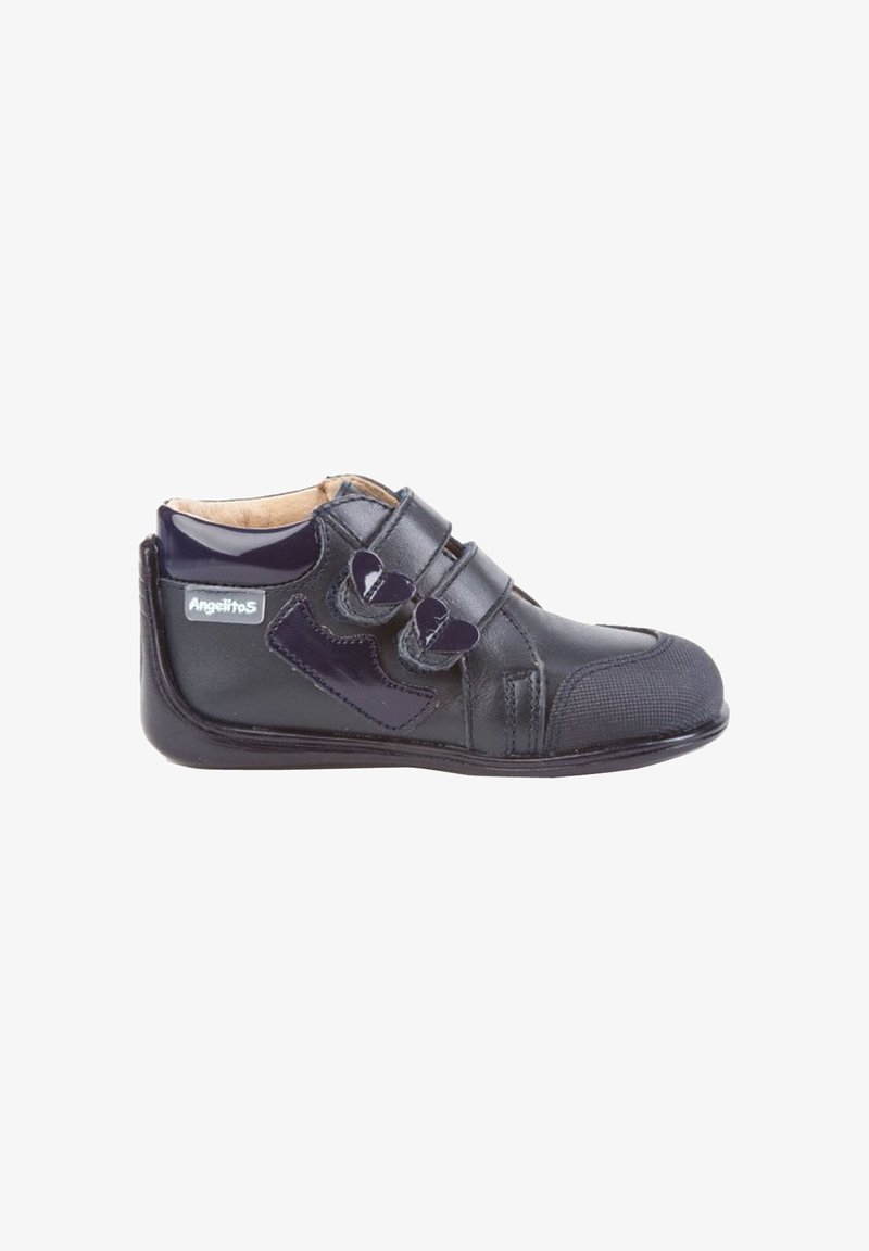 Zapato de cuero negro para niño pequeño con dos correas de velcro en forma de corazón y puntera reforzada protectora.