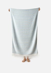 Manta de textura azul y blanca con bordes con flecos, que presenta un patrón tejido en una tela suave y ligera.