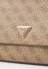Borsa a tracolla marrone con motivo, realizzata in materiale tessile, con loghi incisi e un accento a forma di triangolo in oro sul davanti.