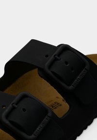 Μαύρο καουτσούκ σανδάλι με δύο ρυθμιζόμενους ιμάντες και ορθογώνιες αγκράφες, εργονομική σόλα και υφασμένη εσωτερική σόλα.