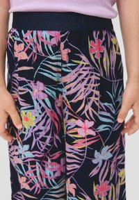 Bloemmotief broek in marineblauw met levendige roze, blauwe en gele bloemen. Heeft een gestructureerd oppervlak en een donkere elastische tailleband.