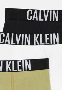 Drie opgevouwen Calvin Klein boxershorts in zwart, wit en olijfgroen met zwarte taillebanden en witte branding.