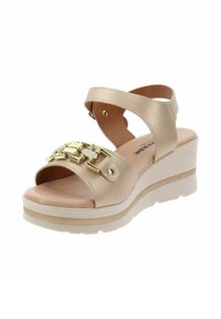Sandali con zeppa in materiale sintetico beige con suola piattaforma. Presentano dettagli in metallo dorato e cinturini incrociati alla caviglia.