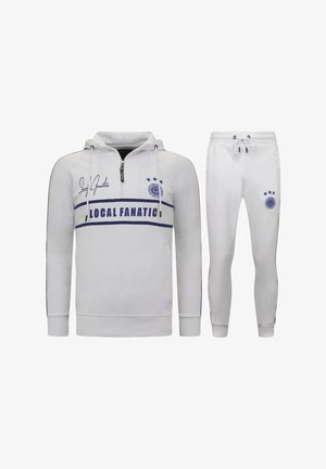 Witte hoodie met rits, zwarte accenten en een blauwe "LOCAL FANATIC" grafiek. Bijpassende witte tapered joggers met trekkoord.