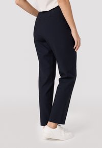 Marineblauwe broek met een op maat gemaakte pasvorm, voorzien van een gladde textuur, zijzakken en een vouw aan de voorkant, gecombineerd met witte sneakers.