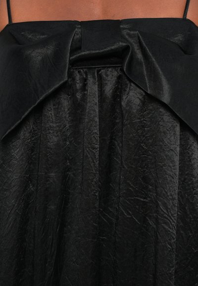 Sort kjole med satinfinish, struktureret bodice med sløjfedetalje og samlet skørt med tekstureret overflade.