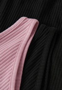 Tissu côtelé superposé en rose et noir, mettant en valeur un design texturé avec des coutures visibles et une finition douce.