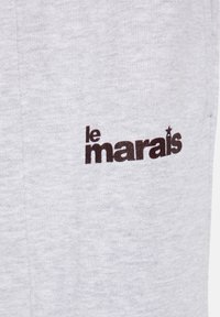 Tissu gris avec texte noir indiquant "le marais" avec une étoile au-dessus de la lettre "i" sur un vêtement.