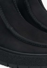 Czarne botki za kostkę wykonane z gładkiej skóry z widocznym przeszyciem. Posiadają teksturowaną gumową podeszwę i smukły design.