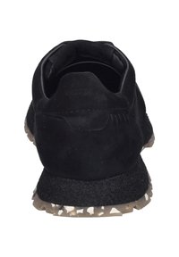 Schwarze Wildledersneaker mit einer strukturierten Gummisohle, die einen gepolsterten Kragen und ein dezentes Logo an der Ferse aufweist. Die Außensohle hat ein gesprenkeltes Design.