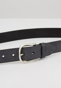 Black leather belt with a textured finish and silver metal buckle, featuring evenly spaced holes for adjustment. Minimalist design.