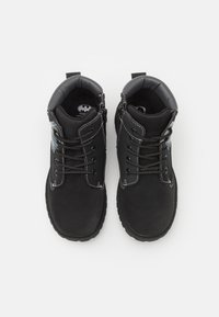 Černé boty s semišovým povrchem, zdobené kontrastním bílým prošíváním, šněrovacím designem a texturovanou gumovou podrážkou. Akcenty s logem Batmana.