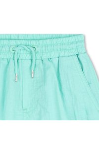 Φωτεινά τιρκουάζ σορτς τζόγκινγκ με ελαστική μέση, κλείσιμο με κορδόνι και πλαϊνές τσέπες. Το υλικό έχει απαλό, ελαφρώς υφασμένο φινίρισμα.