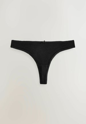 Schwarze Tanga-Unterwäsche aus weichem Stoff mit einem durchsichtigen Einsatz, versehen mit einer Spitzenkante am Bund und einem kleinen Schleifendetail auf der Vorderseite.