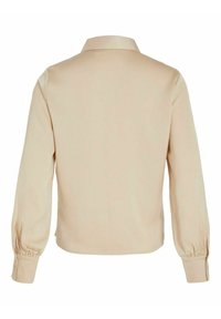 Blouse beige à manches longues avec poignets froncés et bracelets de poignet boutonnés, présentant un col simple et un dos lisse.