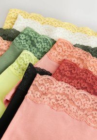 Pile de sous-vêtements féminins pliés avec bordure en dentelle florale dans des couleurs comprenant le rose, le rouge, le noir, le jaune, le blanc et différentes nuances de vert.