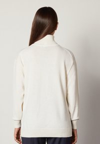 Cremfarbener Rollkragenpullover mit lässiger Passform, gerippten Bündchen und Saum. Sanfte Textur, lange Ärmel und minimales Design. Geeignet zum Drüberziehen.